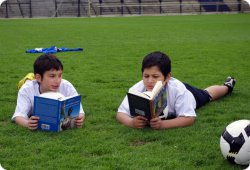 Zwei Kinder liegen Bücher lesend auf dem Rasen. Copyright: LitCam – Fußball trifft Kultur