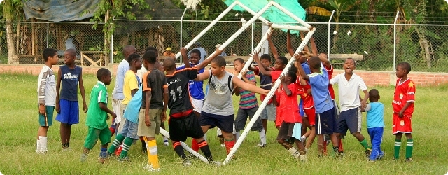 Kinder im Straßenfußballprojekt Colombianitos (Cali, Kolumbien) verrücken gemeinsam ein Fußballtor. Copyright: PLAY!YA